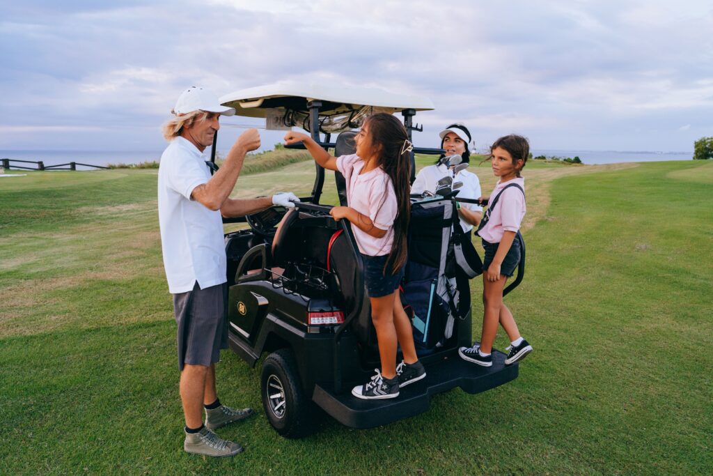 A family enjoys a day at the golf course, bonding with children on a golf cart.
